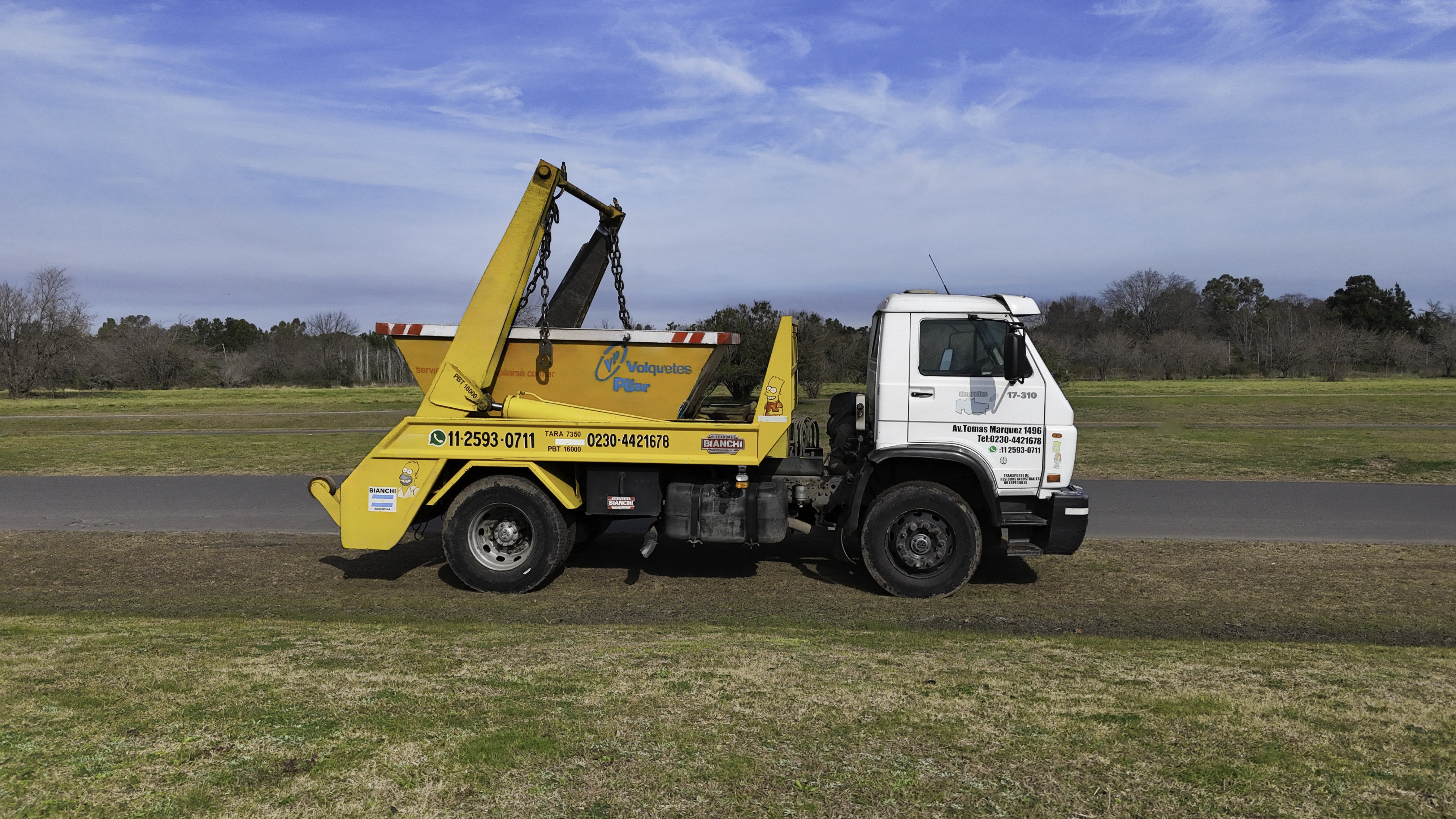 Camión volquete amarillo de Volquetes Pilar con sistema de carga por cadenas en campo abierto